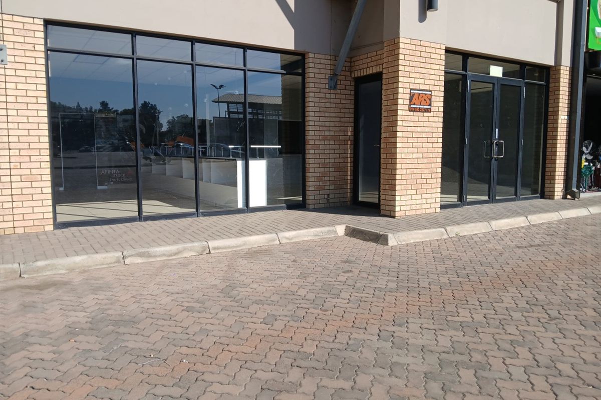 Front exterior view of a retail storefront featuring large glass windows, double entrance doors, and a paved parking area.