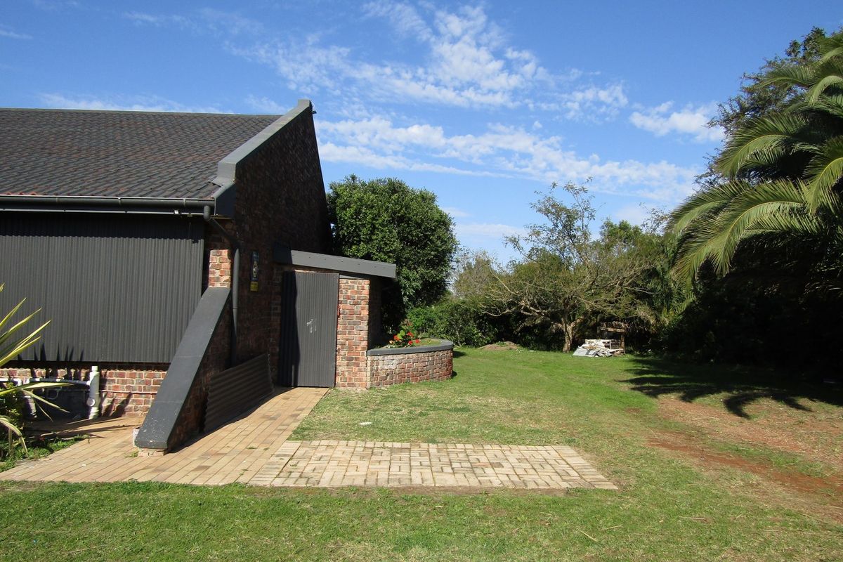 Rear view of the commercial property featuring a brick facade, tiled roof, and a paved patio area leading onto a garden space.