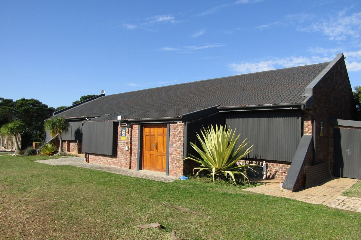 Rear view of a commercial building featuring face brick construction, a tiled roof, and secure metal roller shutters over the windows.
