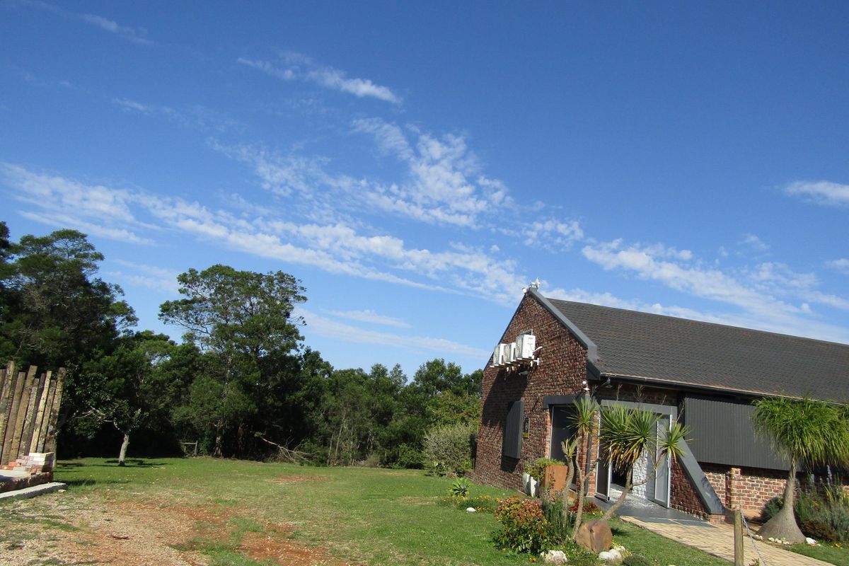 Rear view of a commercial building featuring exposed brickwork, a pitched roof, and external air conditioning units set within a landscaped garden area.