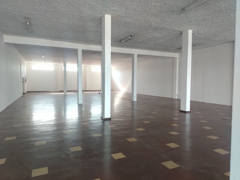 Spacious open-plan retail area featuring structural columns, textured ceilings, and durable vinyl tile flooring, offering a versatile blank canvas for various business layouts.