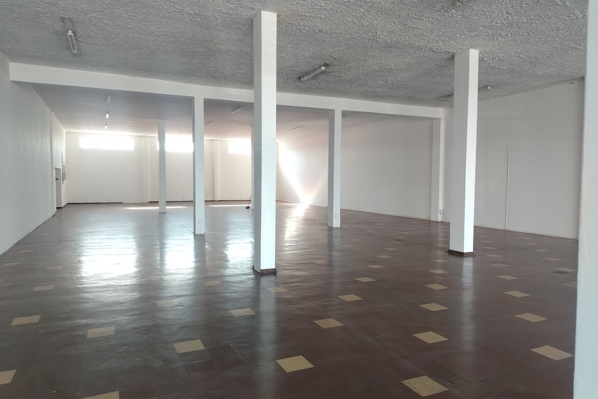 Spacious open-plan retail area featuring structural columns, textured ceilings, and durable vinyl tile flooring, offering a versatile blank canvas for various business layouts.