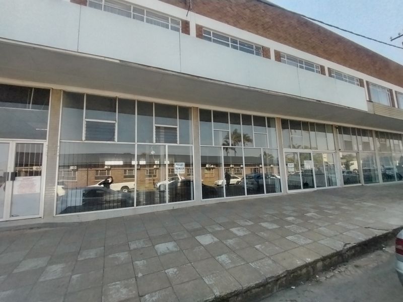 Front exterior view of a commercial retail property featuring large glass display windows and a paved sidewalk frontage.