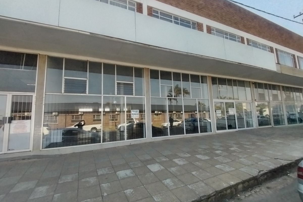 Front exterior view of a commercial retail property featuring large glass display windows and a paved sidewalk frontage.