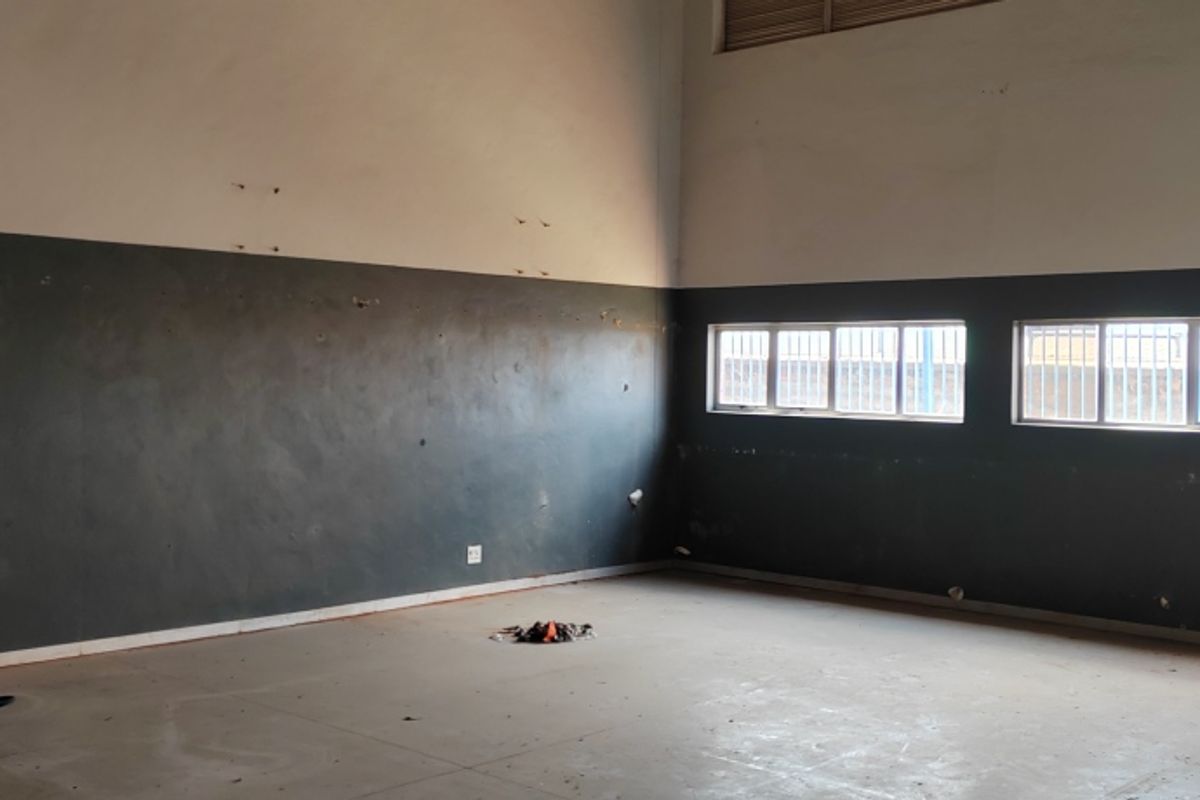 An empty industrial utility space featuring high ceilings, horizontal windows, and dual-tone painted walls with visible surface wear.