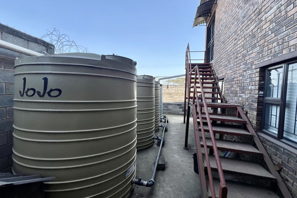 Rear exterior area featuring multiple industrial water storage tanks and an external metal staircase attached to the brick building structure.