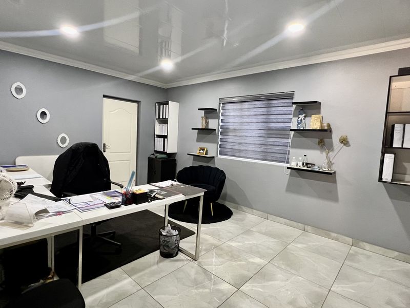A well-maintained office space featuring tiled flooring, recessed downlighting, and built-in shelving units, providing a functional and professional work environment.