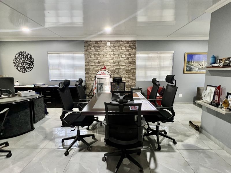 A professional office space featuring a stone veneer accent wall, glossy tiled flooring, recessed lighting, and built-in shelving units.