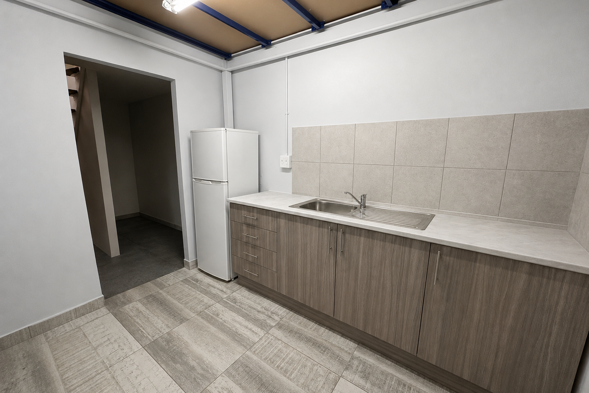 A clean, functional kitchenette featuring modern wood-look cabinetry, a stainless steel sink, tiled backsplash, and exposed industrial-style ceiling beams.