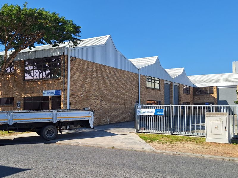 Front exterior view of a commercial industrial property featuring face brick construction, corrugated metal roofing, and secure gated access.
