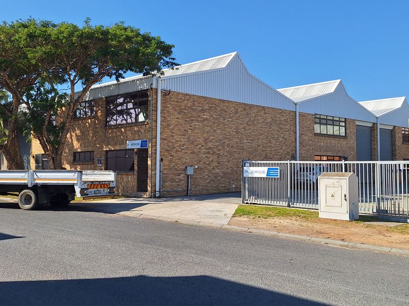 Street view of a commercial industrial property featuring a face brick facade, corrugated metal roofing, and secure gated access.