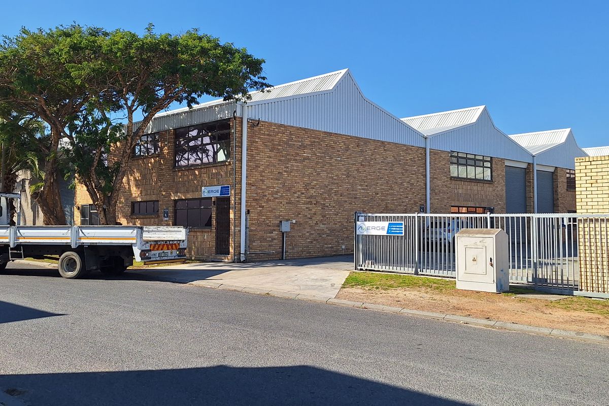 Street view of a commercial industrial property featuring a face brick facade, corrugated metal roofing, and secure gated access.