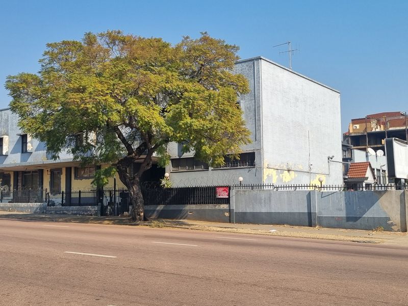 Street view of the property facade featuring a perimeter wall with security fencing and razor wire.