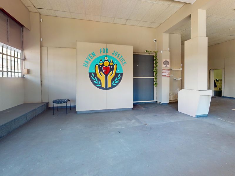 An open-plan commercial space featuring a suspended ceiling, structural columns, and security bars on the windows, suitable for various business applications.