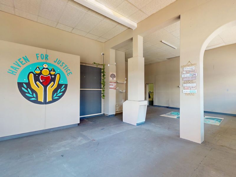 An open-plan commercial space featuring structural columns, an arched entryway, and a suspended ceiling, offering a versatile layout for various business operations.