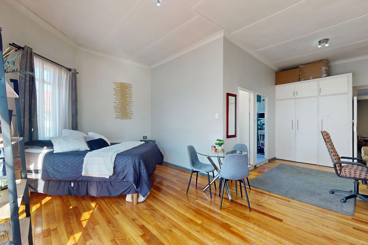 Spacious bedroom featuring polished hardwood flooring, built-in storage cupboards, and neutral wall finishes, offering a functional and well-maintained living space.
