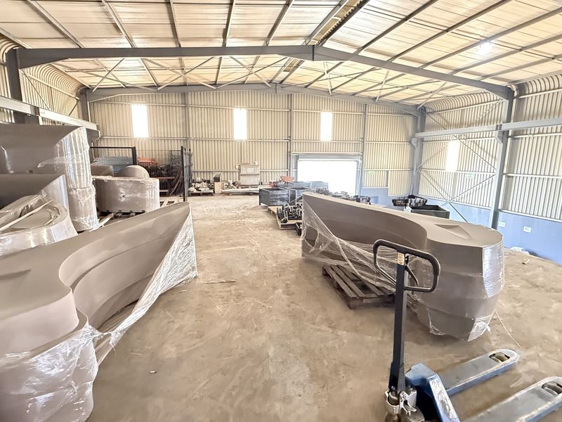 Spacious industrial warehouse unit featuring a steel portal frame, corrugated metal walls, and a durable concrete floor, suitable for storage or manufacturing operations.