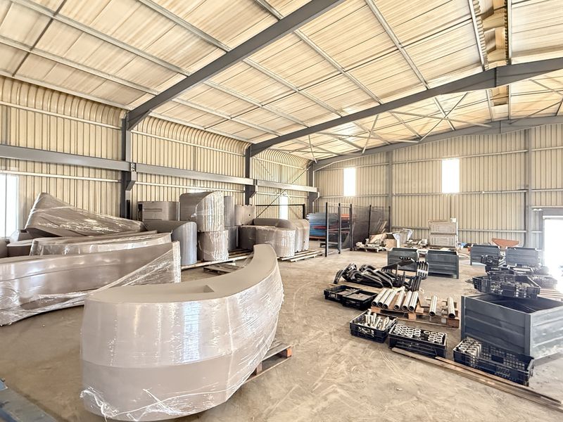 Spacious industrial warehouse featuring a steel portal frame, corrugated metal walls, and durable concrete flooring, suitable for storage or manufacturing operations.
