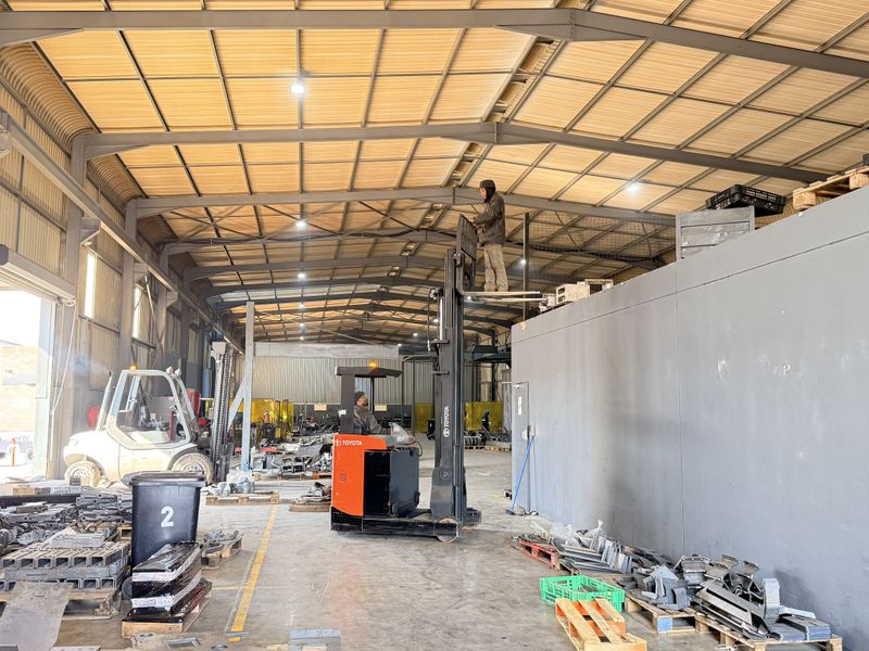 Spacious industrial warehouse featuring a steel portal frame, high-clearance corrugated metal roof, concrete flooring, and integrated partition wall for operational use.