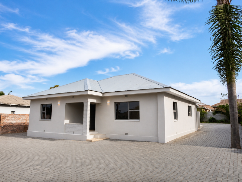 A well-maintained single-story commercial property featuring a clean facade, corrugated metal roof, and extensive paved driveway area.