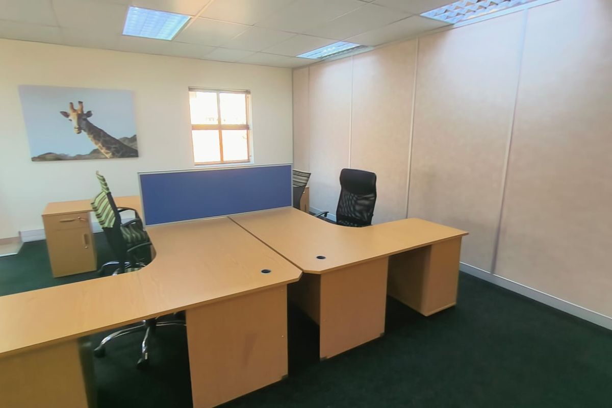A functional office space featuring a suspended ceiling with recessed lighting, carpeted flooring, and modular partition walls.