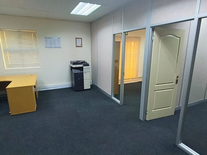 A functional office space featuring aluminum partition walls, carpeted flooring, and integrated ceiling lighting, providing a professional environment for business operations.