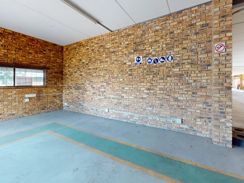 An open-plan industrial utility space featuring exposed brick walls, concrete flooring with painted markings, and surface-mounted electrical infrastructure.