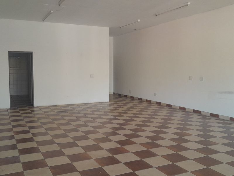 An empty, open-plan office space featuring tiled flooring, fluorescent lighting, and neutral walls, providing a blank canvas for various business configurations.
