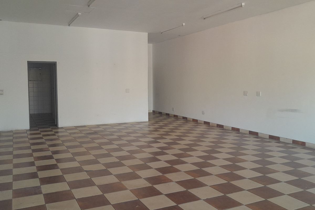 An empty, open-plan office space featuring tiled flooring, fluorescent lighting, and neutral walls, providing a blank canvas for various business configurations.