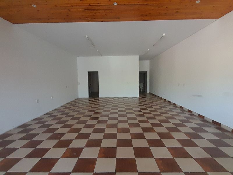 An open-plan office space featuring a timber ceiling, checkered floor tiles, and neutral white walls, providing a versatile layout for various business configurations.