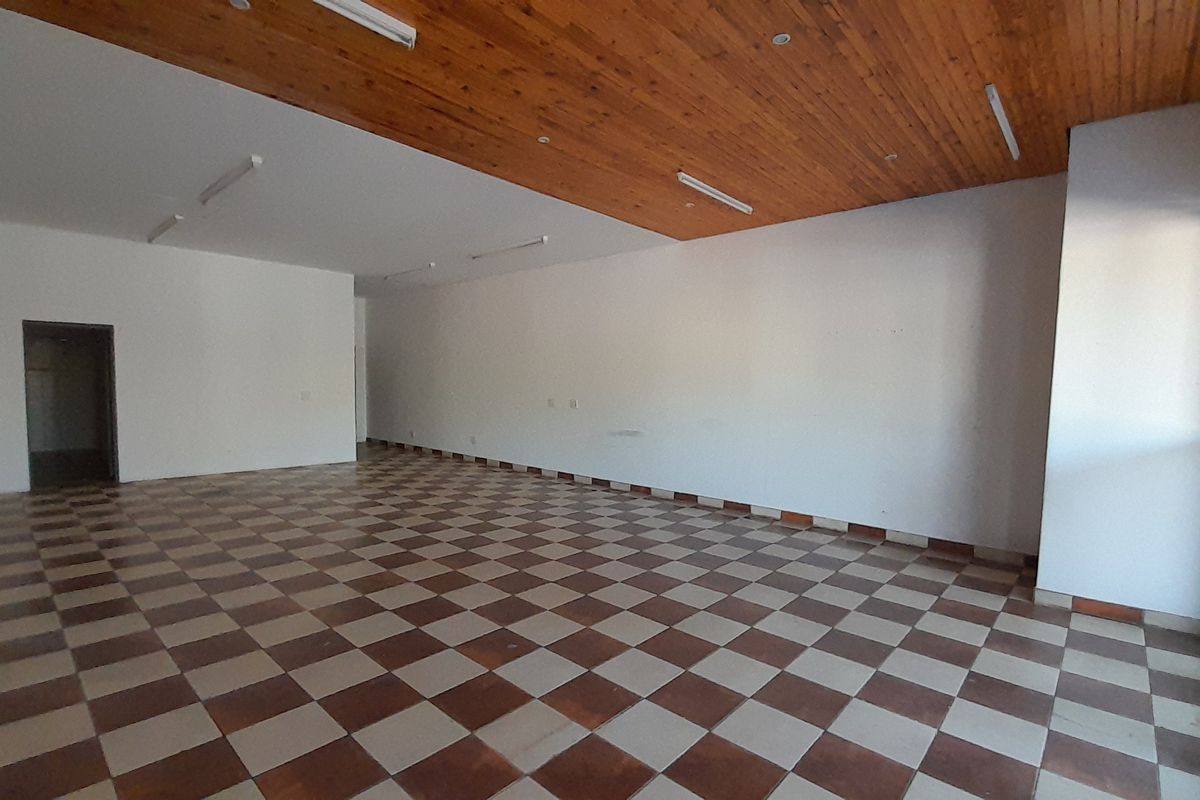 Spacious, empty office area featuring a timber ceiling, checkered tiled flooring, and large sliding glass doors providing natural light.