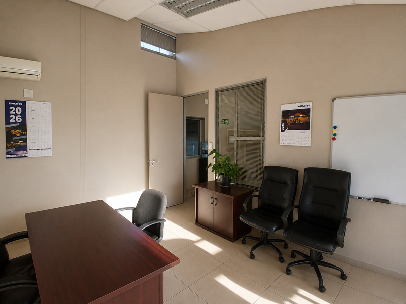 A functional office space featuring tiled flooring, a suspended ceiling, and a split-system air conditioner, providing a clean and professional work environment.