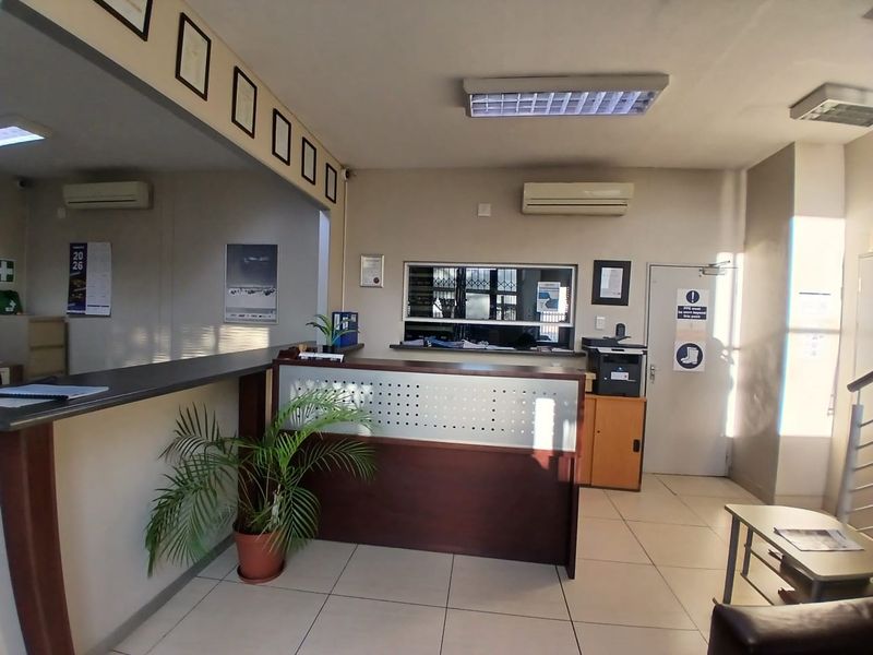 A functional industrial reception area featuring a built-in service counter, tiled flooring, and integrated air conditioning, suitable for professional office or warehouse operations.