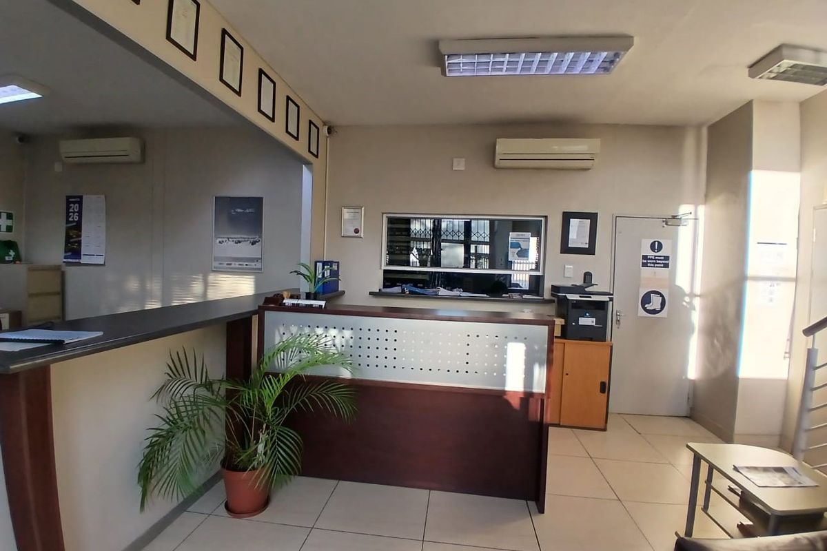 A functional industrial reception area featuring a built-in service counter, tiled flooring, and integrated air conditioning, suitable for professional office or warehouse operations.