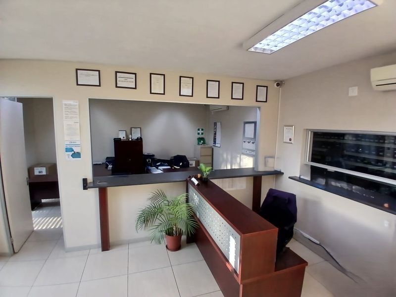 Functional office reception area featuring a built-in service counter, tiled flooring, and integrated air conditioning, suitable for professional industrial or commercial use.