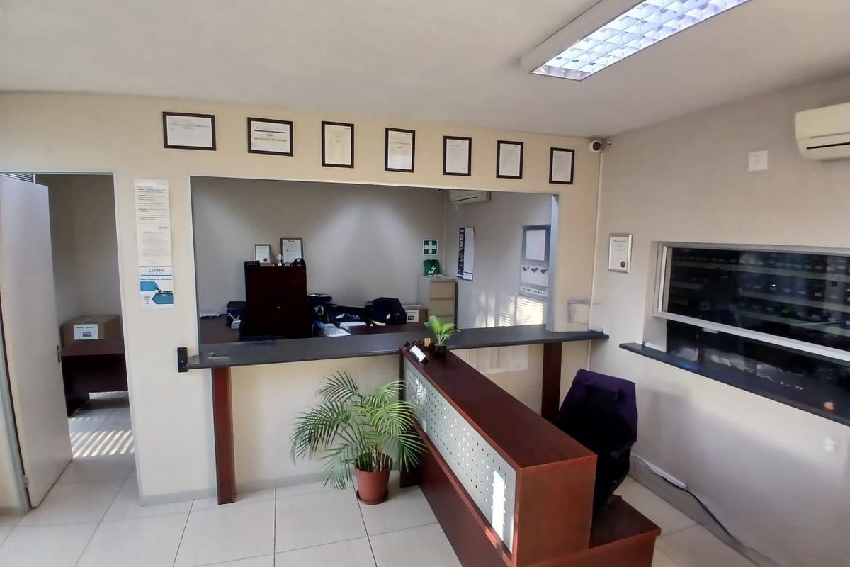 Functional office reception area featuring a built-in service counter, tiled flooring, and integrated air conditioning, suitable for professional industrial or commercial use.