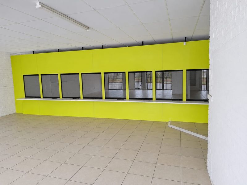 Open plan commercial space featuring a service counter with security glass partitions, suspended ceiling, and tiled flooring.