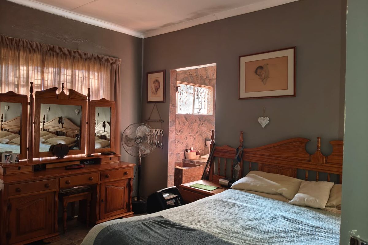 A bedroom featuring tiled flooring and en-suite access, showing visible signs of ceiling water damage and wear requiring maintenance.