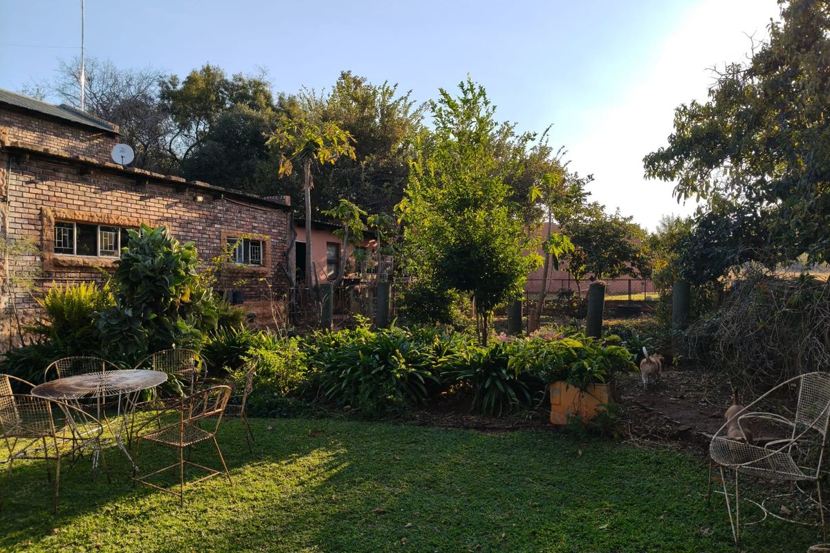 A rear view of the farm property featuring an exposed brick exterior, established garden, and lawn area.