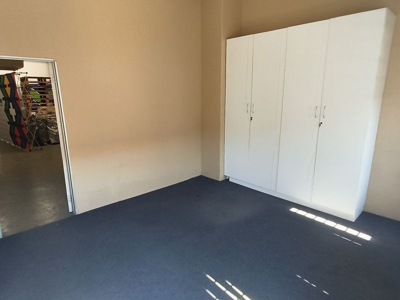 A clean, empty office space featuring built-in white cupboards, carpeted flooring, and neutral wall tones, suitable for a professional workspace.