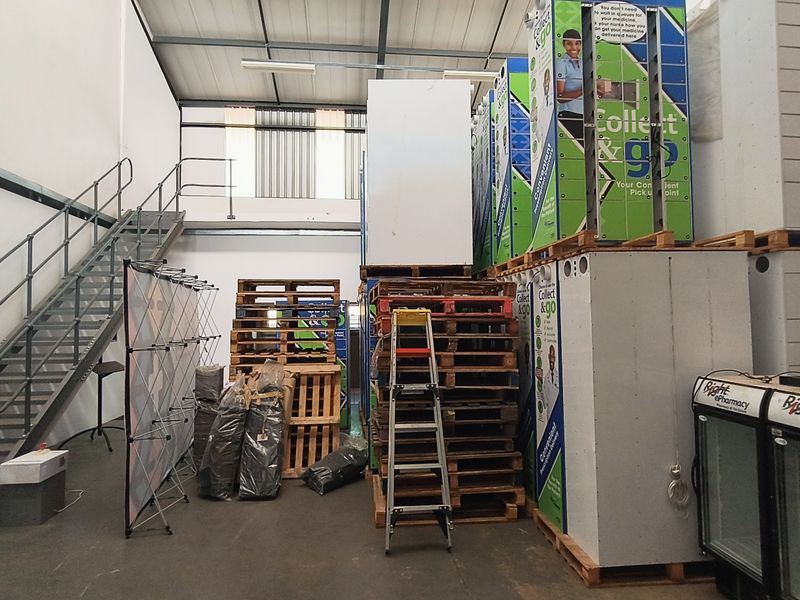 Industrial warehouse space featuring a metal staircase, high ceilings with exposed steel beams, and ample storage capacity for logistics or operational use.