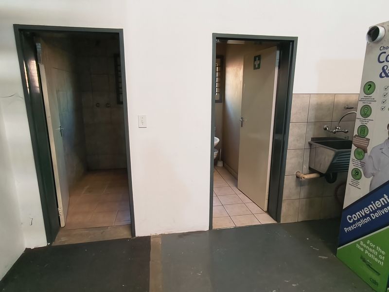 Utility area featuring a wall-mounted sink and access to two separate internal rooms with tiled flooring.