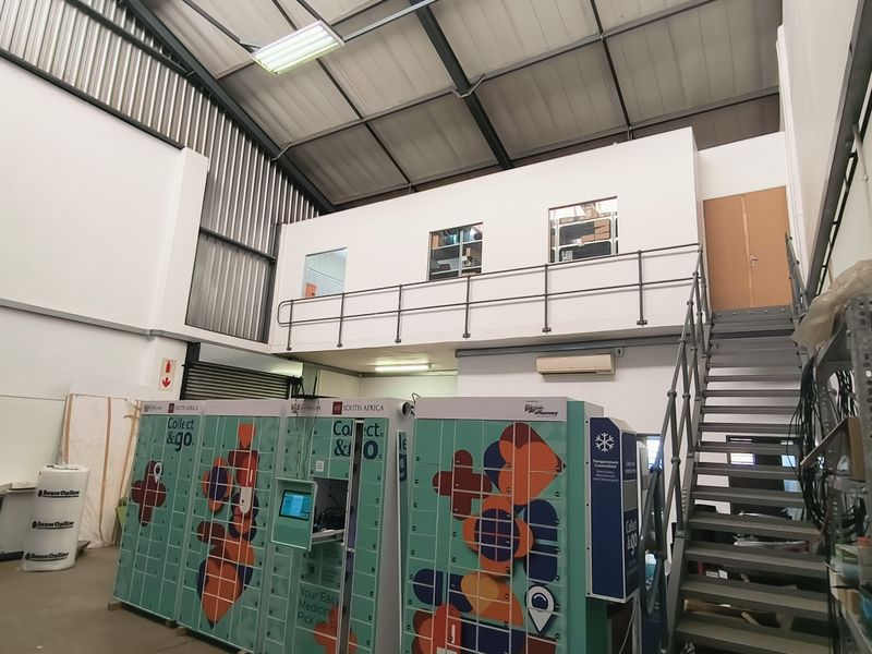 Industrial utility space featuring a mezzanine level with metal staircase, exposed steel roof structure, and integrated climate control systems.