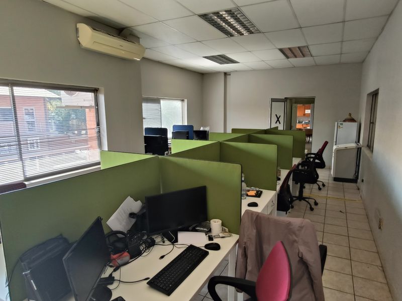 Functional office space featuring tiled flooring, suspended ceilings, integrated lighting, and wall-mounted air conditioning, providing a practical workspace environment.