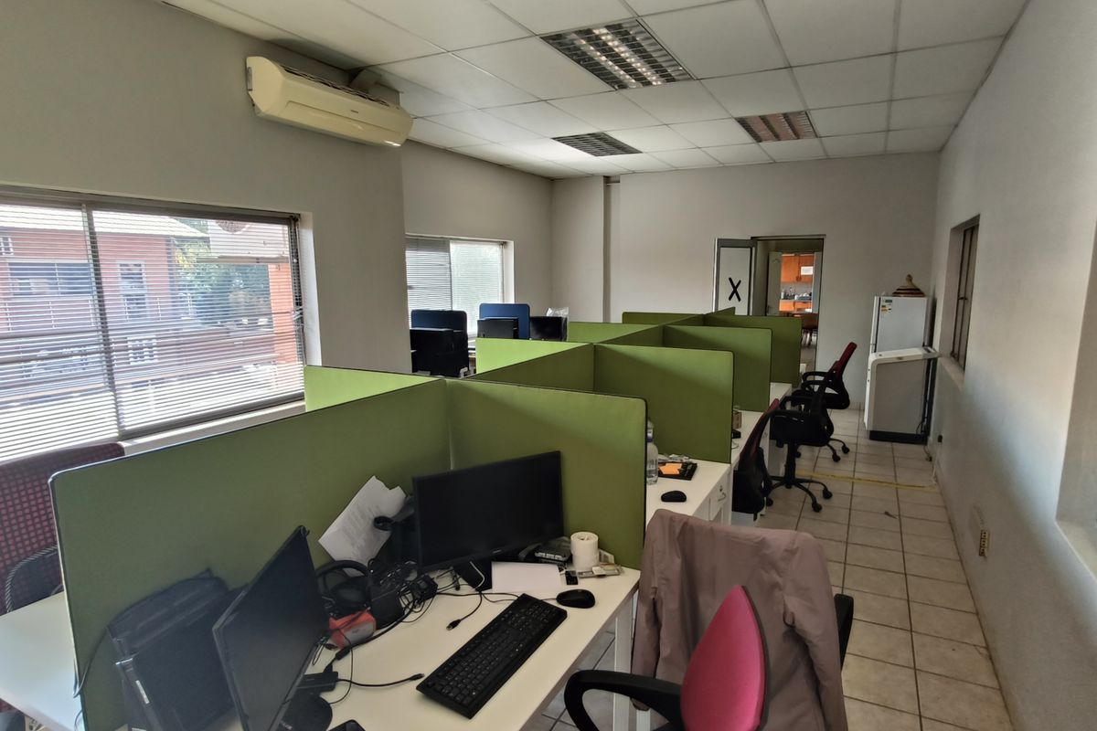 Functional office space featuring tiled flooring, suspended ceilings, integrated lighting, and wall-mounted air conditioning, providing a practical workspace environment.
