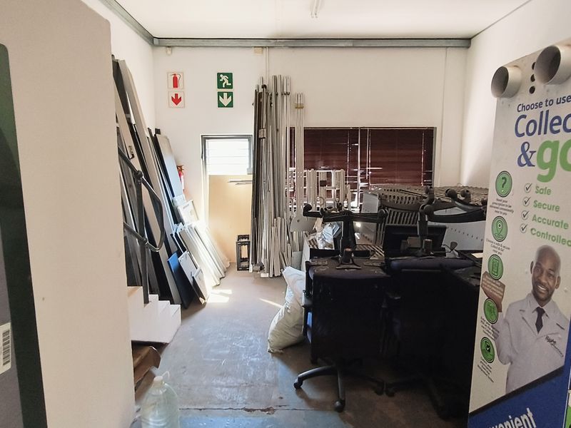 A functional utility or storage space within an industrial property, featuring basic infrastructure and emergency signage.