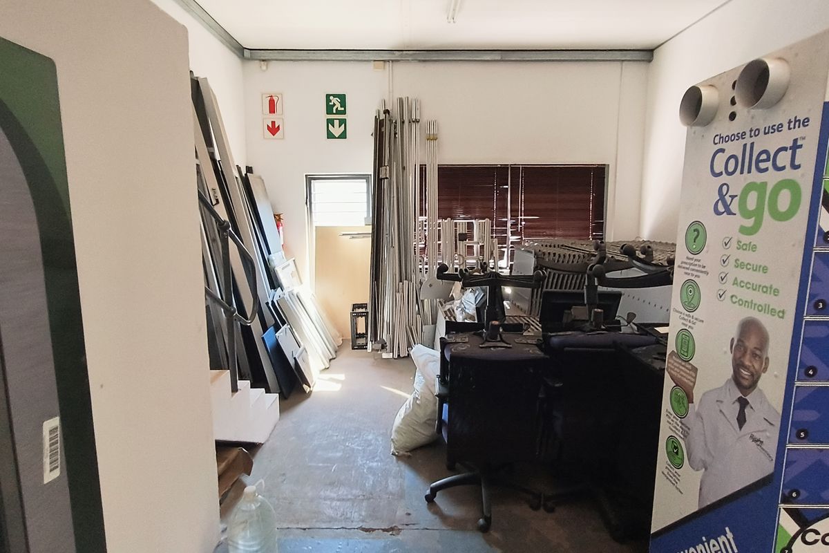 A functional utility or storage space within an industrial property, featuring basic infrastructure and emergency signage.