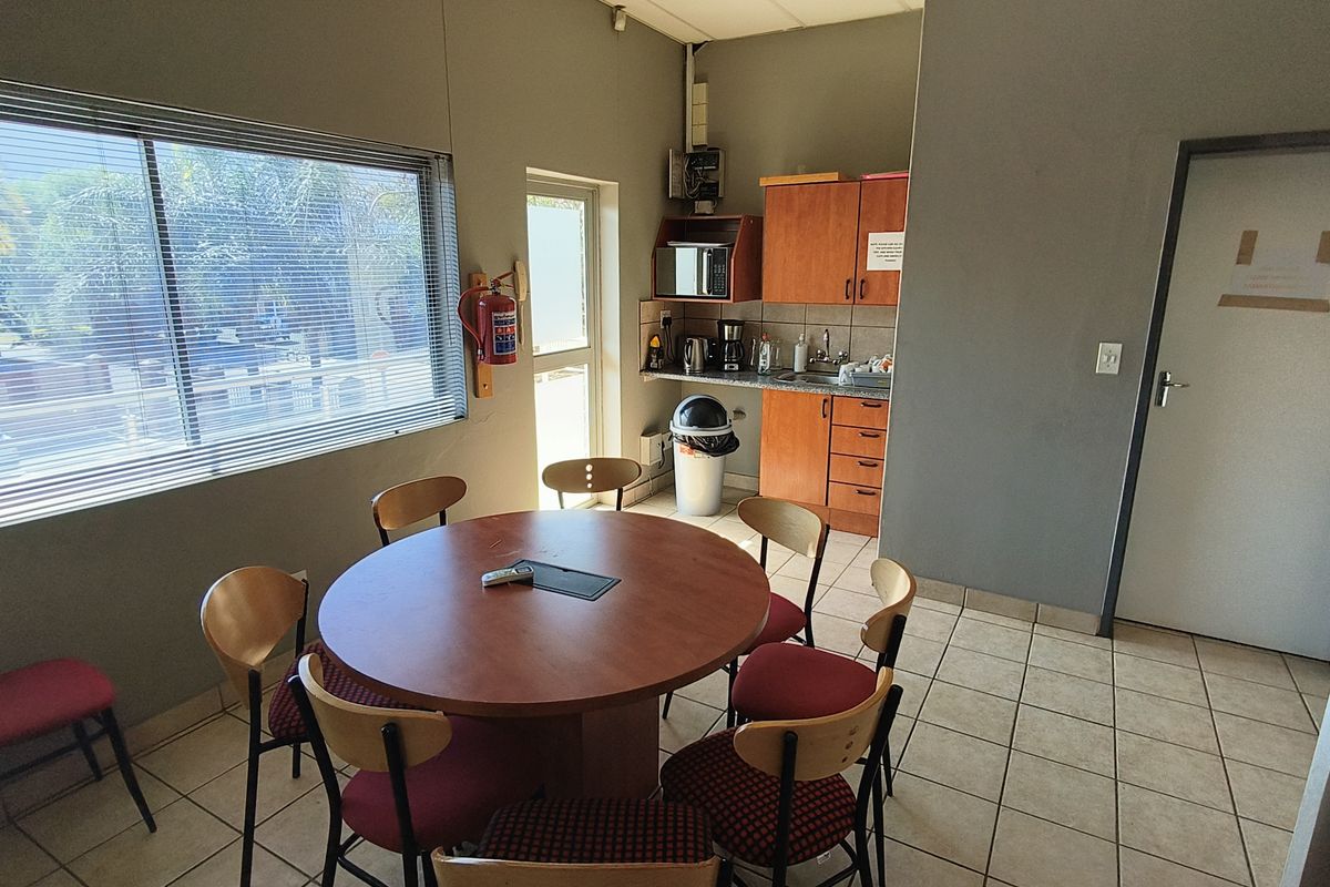 A functional kitchenette area featuring built-in cabinetry, a stainless steel sink, and tiled flooring, suitable for office or industrial staff use.