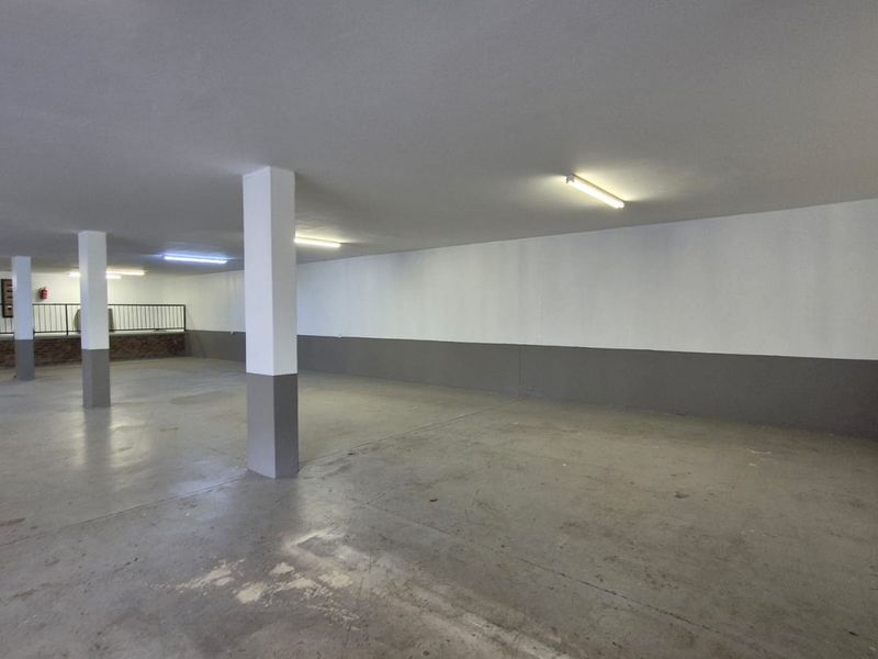Spacious, open-plan industrial garage area featuring concrete flooring, structural support columns, and overhead fluorescent lighting.