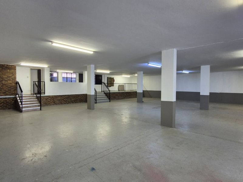 Spacious open-plan industrial area featuring concrete flooring, structural columns, and exposed brick accents, suitable for versatile commercial or storage use.